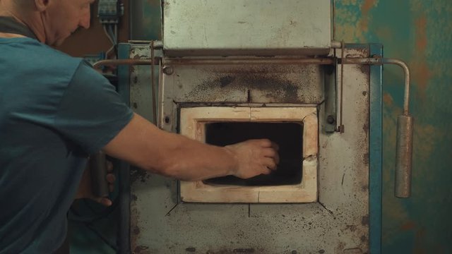 Man use a clay oven. Oven for clay. Man pust a jug inside