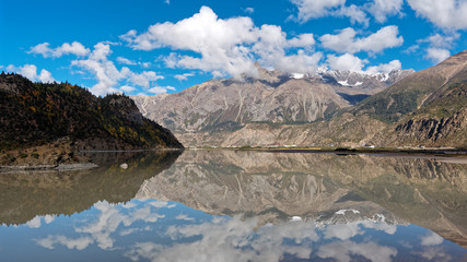 Beautiful landscape of snow mountains with blue sky an white clouds, peaceful reflection on lake, Ranwu lake is a famous landmark along 318 national road in China.