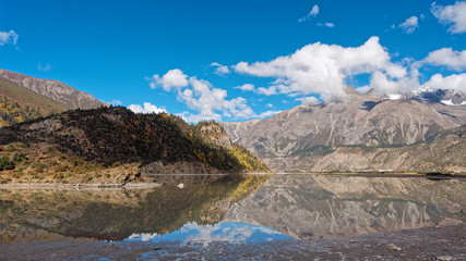 Fototapeta na wymiar Beautiful landscape of snow mountains with blue sky an white clouds, peaceful reflection on lake, Ranwu lake is a famous landmark along 318 national road in China.