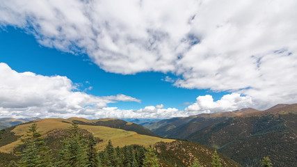 Beautiful landscape of Tibet highland, stone made farmer houses in meadows on the top of mountains with blue sky and white clouds. 