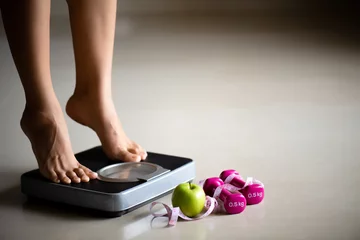 Poster Female leg stepping on weigh scales with measuring tape and green apple. Healthy lifestyle, food and sport concept. © Siam