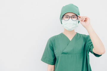 Portrait of young Asian nurse with surgeon uniform, wearing a surgical mask for protection from inhaling airborne bacteria or virus disease.