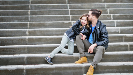 Fashionable stylish family portrait for a walk. Dad and daughter posing on the city stairs....