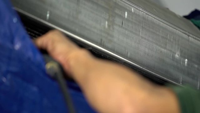 slow-motion of technician service using water spray are cleaning the air conditioner indoors