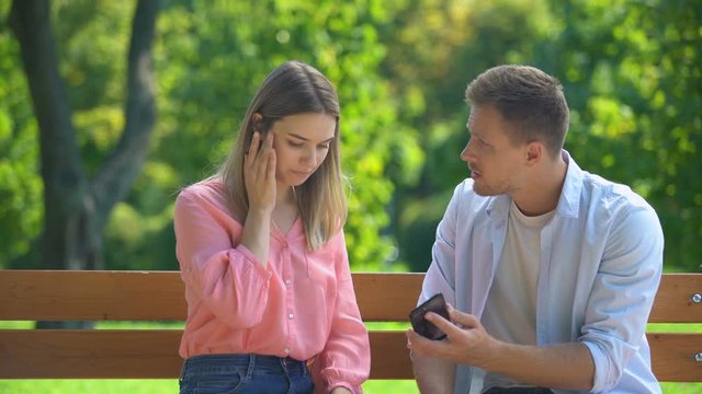 Guy checking girlfriends phone asking about chats with other men, jealousy