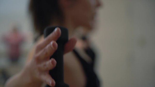 A close up of a lady hands in a gym exercising of her hands with small dumbbells in a gym.