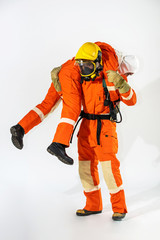 Selective focus wide shot firefighter in fire suit carrying unconscious man on his shoulders in...