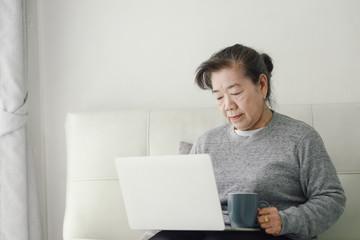 Asian senior woman using laptop at home, lifestyle concept.