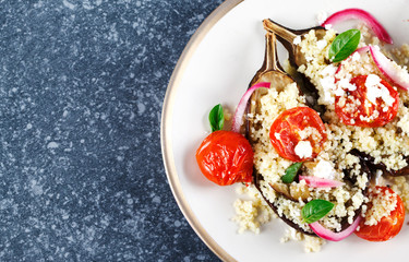 Baked eggplant stuffed with couscous, tomatoes, feta and basil leaves.