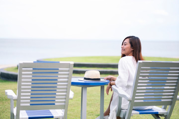 A beautiful asian woman sitting on wooden bench by the sea