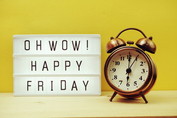 Happy Friday text in lightbox with alarm clock on yellow background