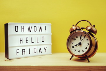 Hello Friday text in lightbox with alram clock on yellow background