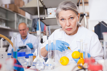 Female lab technician injecting reagent into lemon