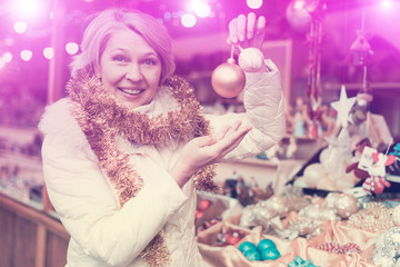 Smiling woman choosing Christmas toys at Christmas market