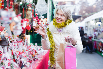Portrait of happy woman in tinsel choosing Christmas decoration