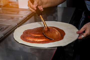 Closed up hand of chef the process of making pizza at kitchen restaurant.