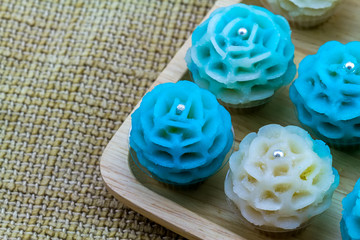 Close up traditional Thai dessert flower shape stuff with crush soybean and taro (Thai name kanom Chor phaka) in wooden basket on fabric sisal.