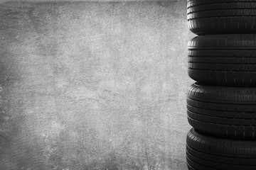 A stack of tires on grunge background with copy space. - obrazy, fototapety, plakaty