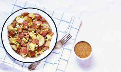 German potato salad with fried bacon and mustard dressing. traditional for oktoberfest festival. top view. copy space.