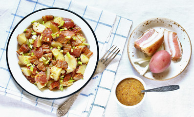 German potato salad with fried bacon and mustard dressing. traditional for oktoberfest festival. top view. copy space.