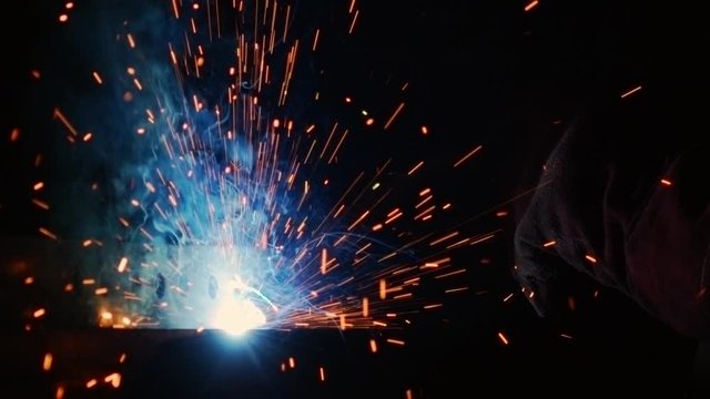 Close up of a welding arc, with sparks flying through the air.