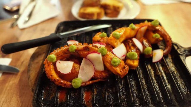 eating dinner with friends in modern restaurant, roasted octopus, potatoes and vegetables