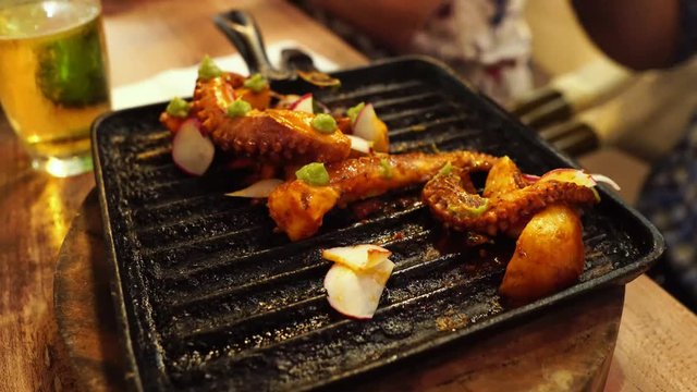 eating dinner with friends in modern restaurant, roasted octopus, potatoes and vegetables