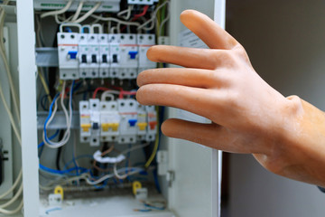 worker in rubber gloves opens the door switchboard