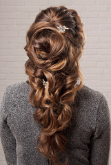 Female hairstyle oriental tail on the head of a brown-haired woman back view.