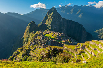 Inca ruin of Machu Picchu at sunset with the last sun rays illuminating the lost city seen from the agriculture terraces, Cusco Region, Peru.
