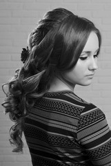 Close-up professional female hairstyle with rosebuds on long brown-haired hair of a brown-haired...