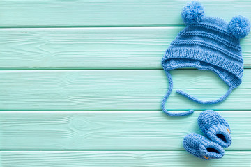 Blue knitted set for kids on mint green wooden background top view space for text