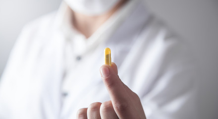 Doctor hand holding a yellow pill.