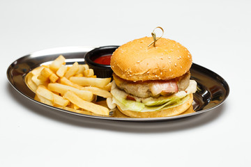 burger on a mirror plate with sauce and a potatoes