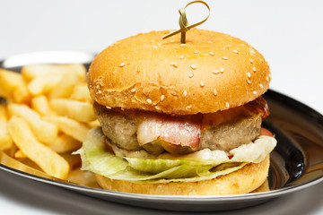 burger on a mirror plate with sauce and a potatoes