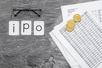 IPO with coins and calculation table on office desk gray textured background top view