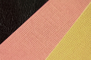 Different color cardboard sheets on a dark leather surface close up. Abstract background