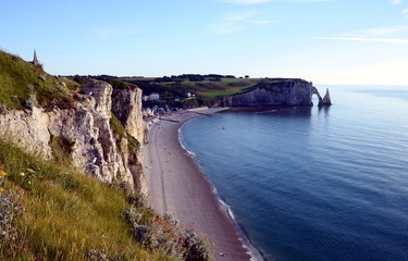 Fototapeta na wymiar Famous white chalk cliffs of Etretat city in Normandy, France in sunset light. Beautiful arche and empty beach.