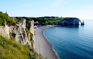 Famous white chalk cliffs of Etretat city in Normandy, France in sunset light. Beautiful arche and empty beach.