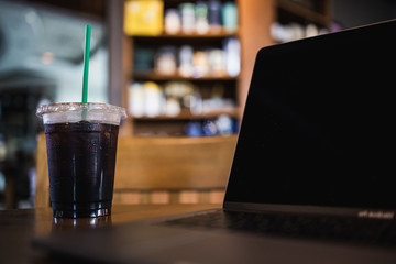 Takeaway cup of ice americano coffee with notebook  in cafe