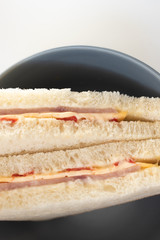Top view on cut of sandwich with ham, cheese and tomatoes in dark plate