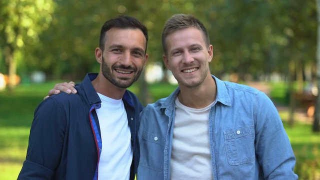 Best male friends hugging and smiling at camera outdoors, cheerful relations