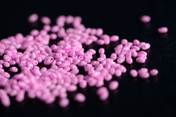 Bright pink twin beads scattered on a dark surface close up