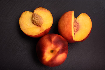 Peaches lie on a black stone slate, place for text
