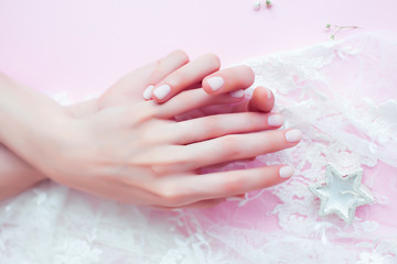 Fototapeta premium woman hands with manicure among white lace on pink background, cosmetic concept