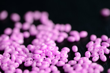 Bright pink twin beads scattered on a dark surface close up