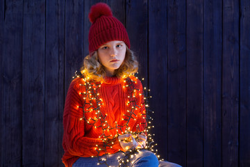 Fototapeta premium girl in red hat with christmas light on wooden background