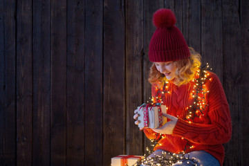 girl in red hat with christmas light on wooden background