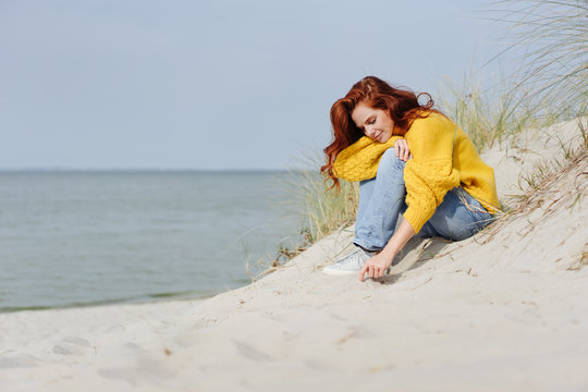 Thoughtful young woman drawing in beach sand