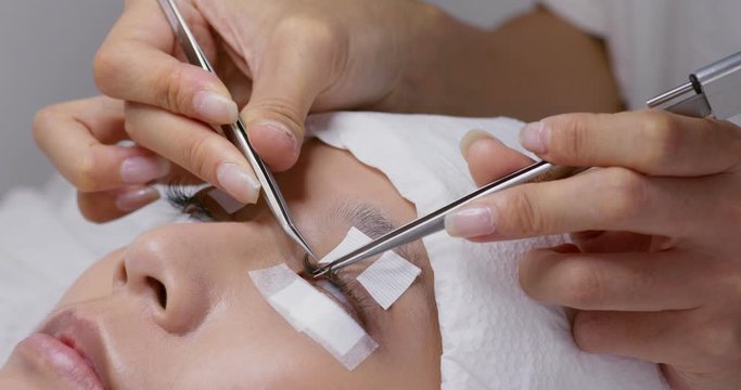 Female woman having eye lash extension in beauty salon
